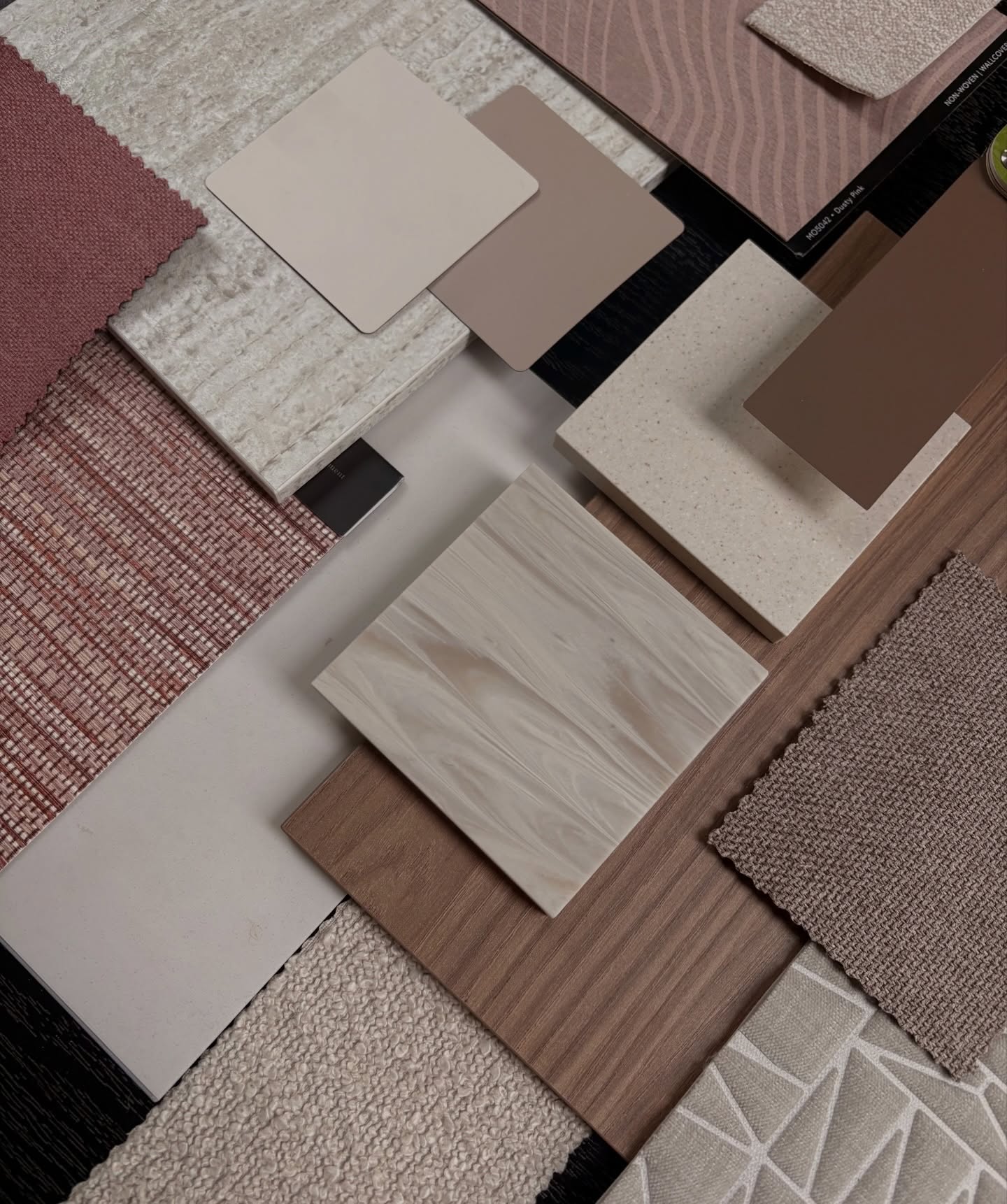 Een verzameling van verschillende materialen en texturen, waaronder stof, keramiek en hout, gepresenteerd op een tafel.